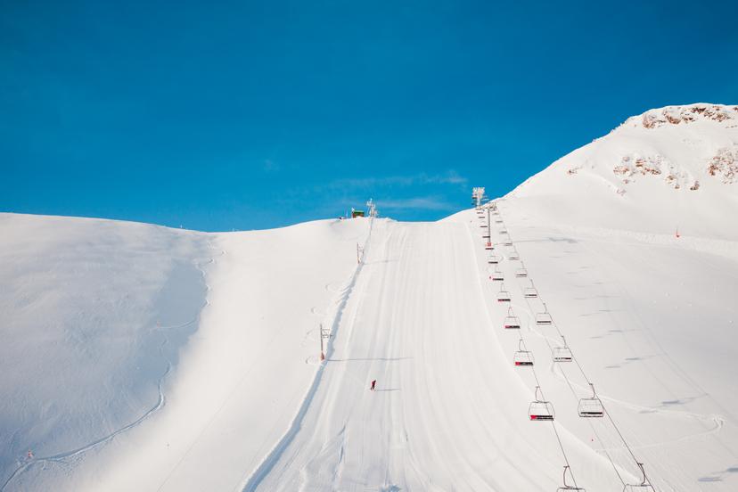 Skier carving down wide open empty slope at Arinsal ski resort Andorra